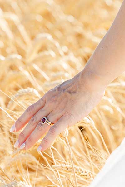 Photo de la main d'une mariée avec son alliance de mariage dans un champ de blé dans la Drôme