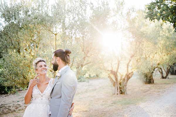 Photo d'un couple de marié qui se promène dans une allée bordée d'oliviers à Nice