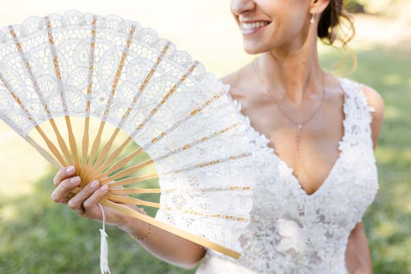 Mariée tenant un éventail en dentelle blanche, mariage d'été en Provence.