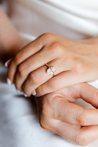 Gros plan sur une main de femme portant une bague de fiançailles avec un diamant ovale sur anneau en or.