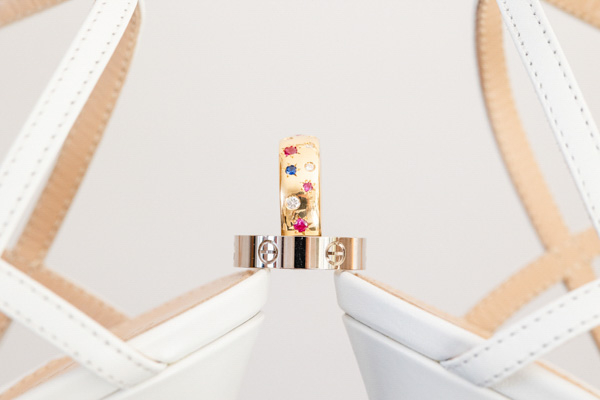 Alliances de mariage Cartier et or serti de pierres sur chaussures blanches.