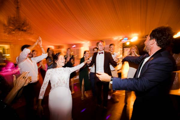 Invités et mariés dansant lors d'une soirée de mariage festive en intérieur.