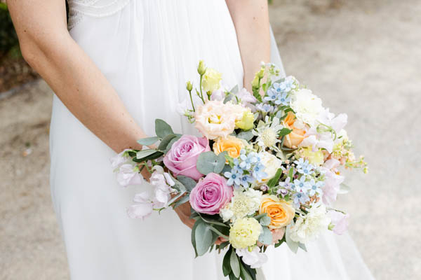 Gros plan sur un bouquet de mariée composé de roses, lysianthus et fleurs des champs pastels.