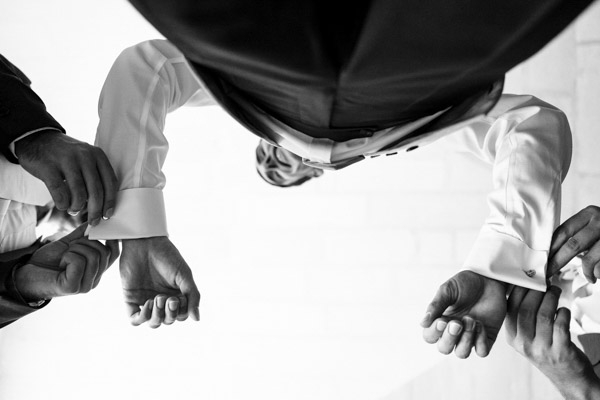 Vue artistique en contre-plongée et noir et blanc des mains ajustant les boutons de manchette du marié.