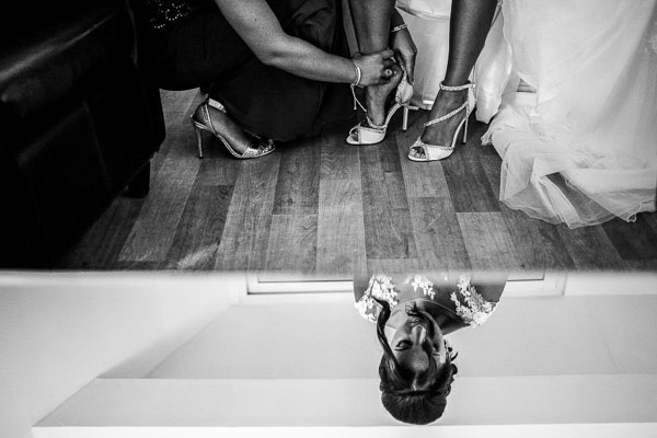 Mise des chaussures de la mariée avec un reflet artistique au sol.