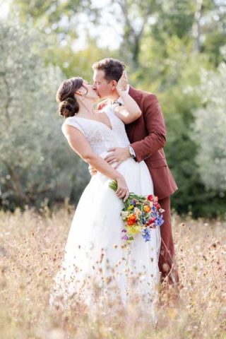 Portrait d'un couple de mariés s'embrassant tendrement dans un champ de fleurs sauvages en Provence.