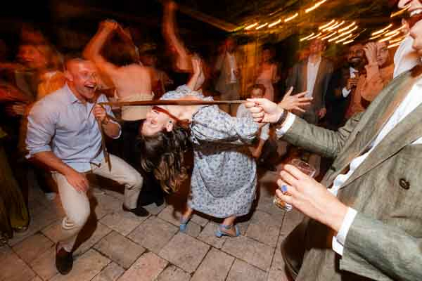 Invitée s'amusant à faire le limbo avec une cravate sur une piste de danse de mariage en extérieur.