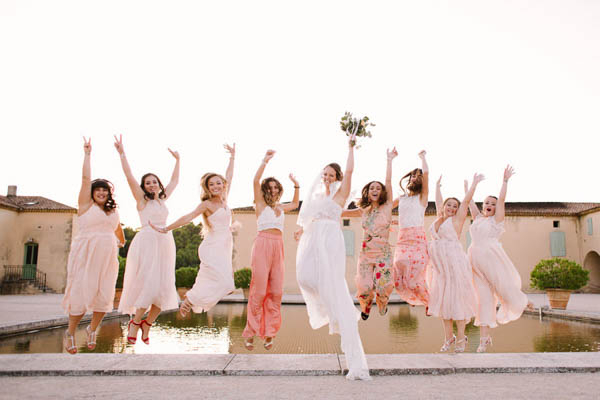 Mariée et ses demoiselles d'honneur sautant de joie devant un bassin.