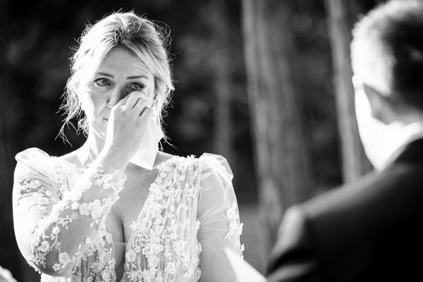Portrait serré en noir et blanc d'une mariée essuyant une larme d'émotion.