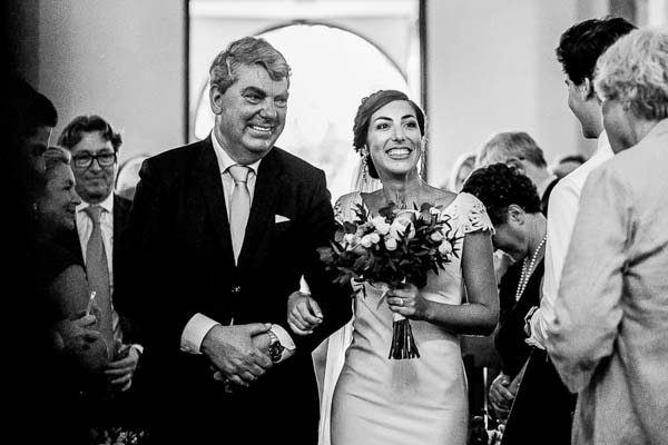 Photographie en noir et blanc du père de la mariée l'accompagnant à l'autel avec émotion.