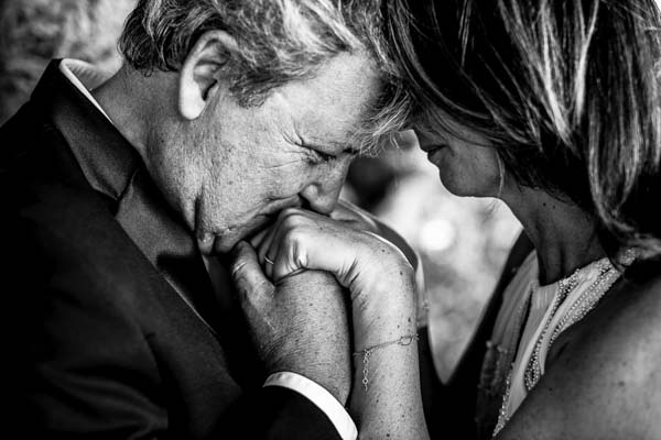 Gros plan en noir et blanc d'un homme embrassant la main d'une femme.