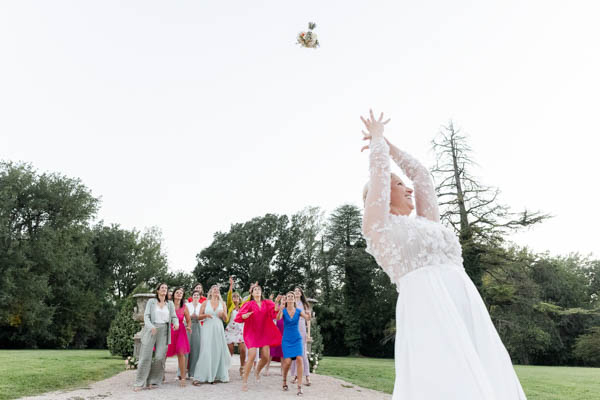 La mariée lance son bouquet de fleurs à ses amies dans le parc d'un domaine en Provence.