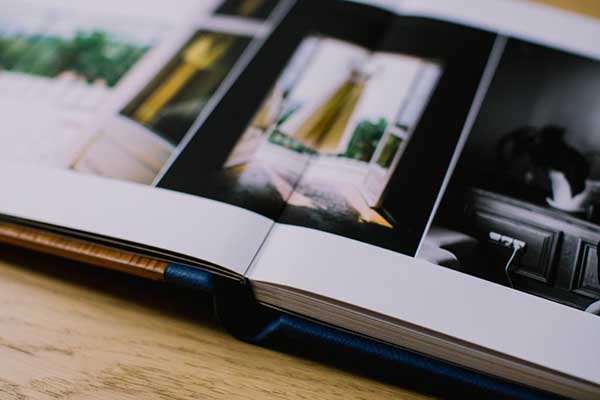 Gros plan sur les pages épaisses et la reliure d'un livre album photo de mariage professionnel ouvert sur une table en bois.