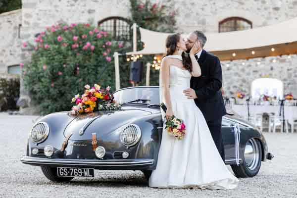 Mariés s'embrassant devant une Porsche ancienne lors d'un mariage en Provence.