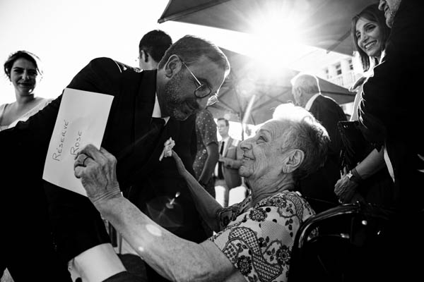 Marié saluant avec tendresse une dame âgée lors du cocktail de mariage.