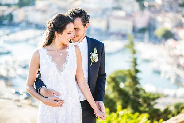 Portrait romantique d'un couple de mariés sur les hauteurs du Château de Cassis avec vue panoramique sur le port et la mer.