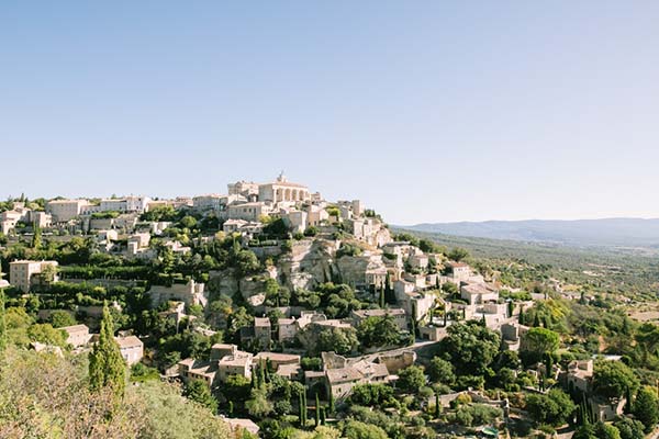 Vue panoramique sous un ciel bleu du village perché de Gordes dans le Luberon, lieu de réception de prestige pour un mariage en Provence.