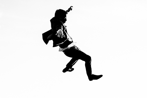 Marié sautant en l'air avec une silhouette épurée sur un fond blanc pour un effet artistique minimaliste.