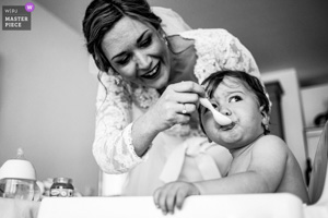 Plan serré en noir et blanc d'une mariée attentionnée s'occupant d'un bébé pendant la matinée de son mariage dans le Sud de la France.