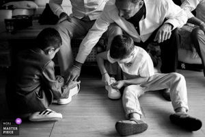 Photographie de mariage primée en noir et blanc montrant deux jeunes garçons s'aidant mutuellement à mettre leurs chaussures lors des préparatifs en Provence.