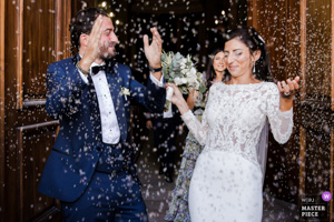 Photographie de mariage primée montrant un couple de mariés rayonnants sous une pluie de riz lors de leur sortie d'église en Provence.