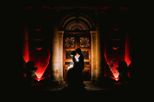 Silhouette des mariés devant une porte monumentale éclairée en Provence de nuit.