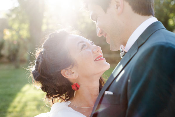 Gros plan d'un couple de mariés se regardant tendrement à contre-jour.