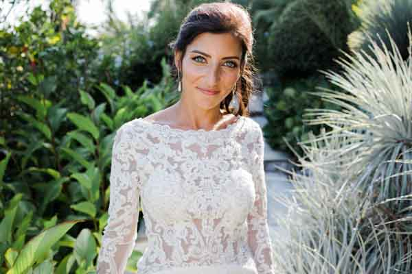 Portrait lumineux d'une mariée portant une robe en dentelle travaillée dans un jardin méditerranéen.
