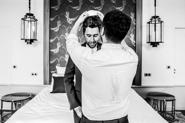 Photo en noir et blanc d'un proche ajustant la kippa sur la tête du marié lors des préparatifs.