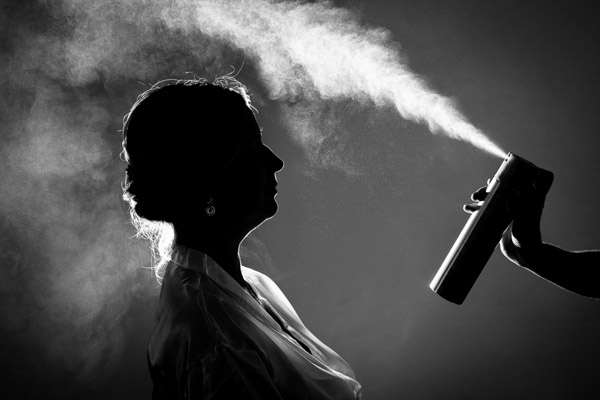 Silhouette de mariée en noir et blanc pendant la coiffure avec un jet de laque rétro-éclairé.