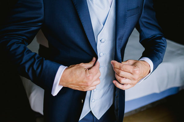 Gros plan d'un marié ajustant son gilet de costume bleu en Provence.