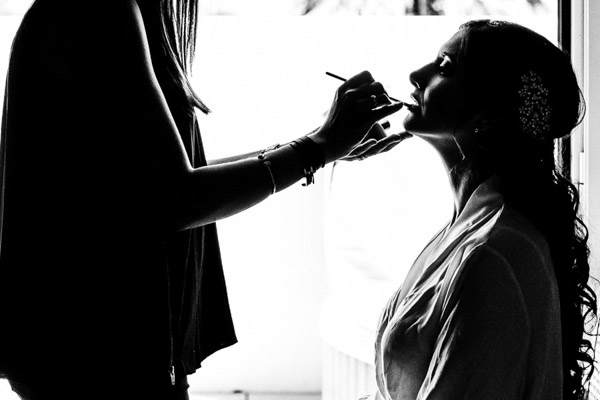 Silhouette en noir et blanc de la mariée se faisant maquiller.