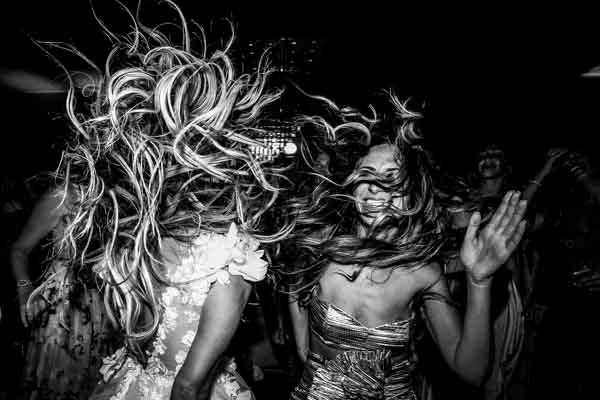 Photo dynamique en noir et blanc de la mariée et ses amies dansant à la soirée.
