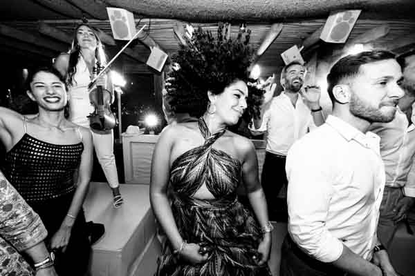 Photographie dynamique en noir et blanc d'invités dansant avec ferveur lors d'une réception.