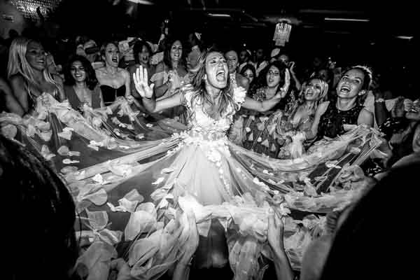 Ambiance de fête effrénée avec invités dansant autour d'une mariée radieuse, sous les lumières d'une soirée de mariage en Provence.
