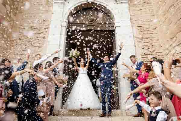 Mariés sortant de l'église sous une pluie de pétales de roses en Provence.
