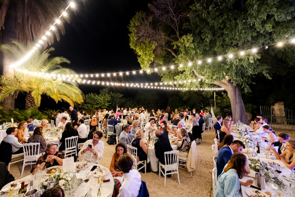 Invités profitant du dîner de mariage en extérieur à la Villa Brignac sous un éclairage chaleureux.
