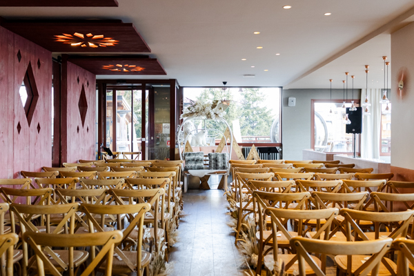 Salle de cérémonie laïque avec chaises en bois et vue sur les pistes à l'Alpe d'Huez.