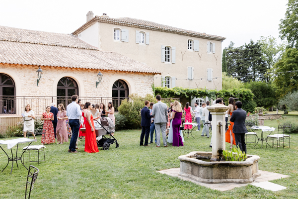 Invités profitant du vin d'honneur dans le jardin du Domaine de Romanil, près de la fontaine, lors d'un mariage à Saint-Rémy-de-Provence.