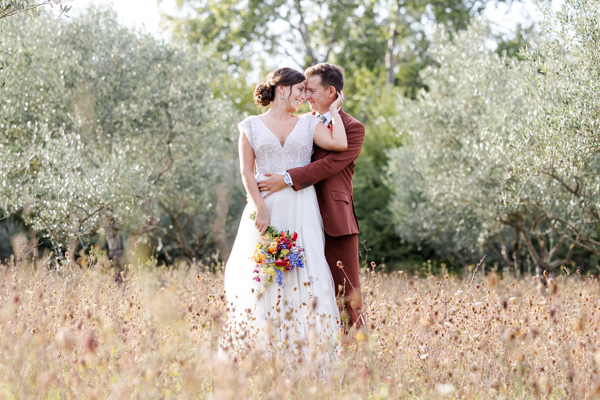 Couple de mariés s'enlaçant dans un champ de fleurs sauvages au Domaine de Brès, photo de mariage bohème par un photographe dans le Gard.