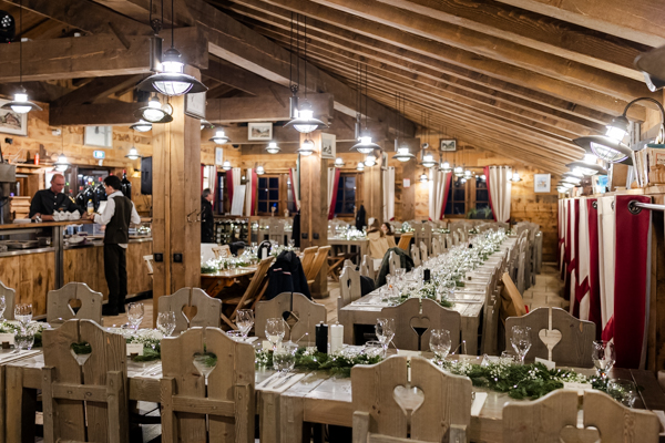 Intérieur chaleureux du Clos Bernard avec de grandes tables en bois décorées pour un dîner de mariage.