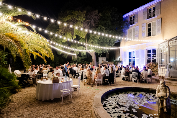Dîner de mariage en extérieur avec guirlandes guinguettes et fontaine à la Villa Brignac.