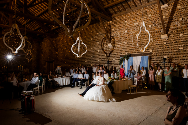Les mariés assis au centre de la piste de danse, émus, écoutant un discours pendant la soirée de mariage au Château de Vergières.