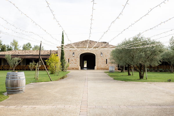 Entrée du Domaine de Brès à Goudargues, un lieu de réception de mariage en pierre avec une allée et des guirlandes lumineuses.