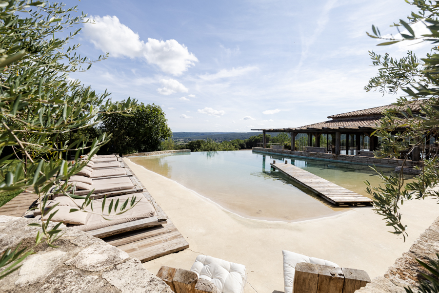Espace détente avec piscine naturelle de style lagon et transats au Domaine de Brès, lieu de mariage à Goudargues.