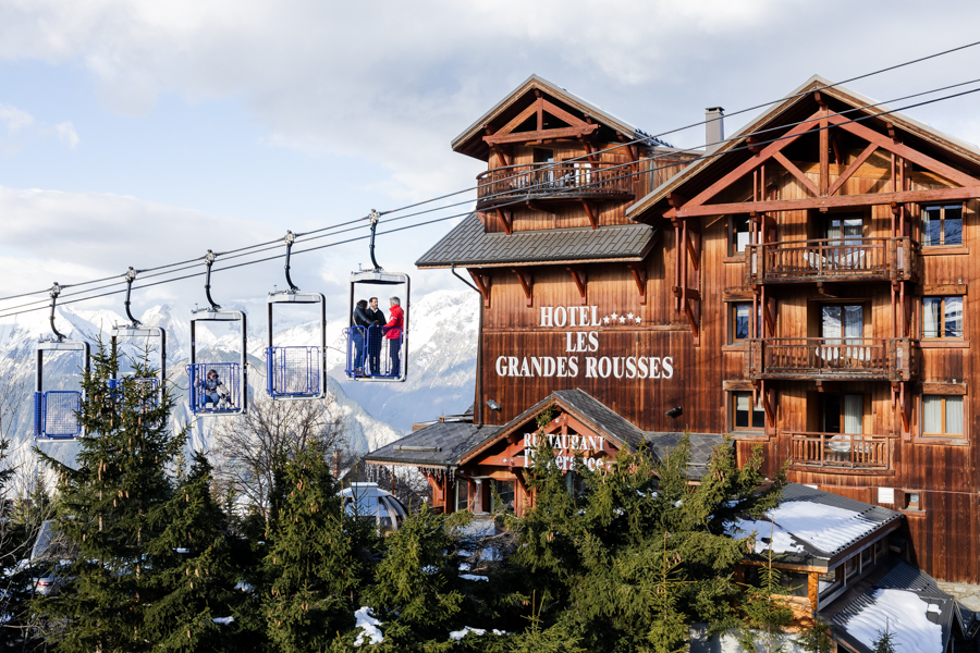 Façade en bois de l'Hôtel Les Grandes Rousses 5 étoiles avec remontées mécaniques.