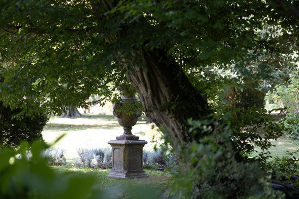 Vase Médicis en pierre dans le parc ombragé du Domaine de Romanil, détail de l'ambiance d'un mariage en Provence.