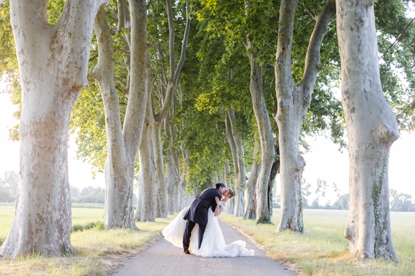 Mariés s'embrassant dans la célèbre allée de platanes du Château de Vergières, photo de couple romantique réalisée par un photographe de mariage.