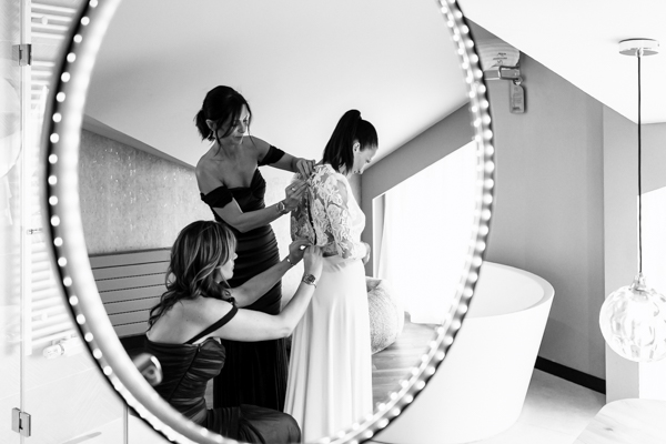 Photographie en noir et blanc des préparatifs de la mariée dans le reflet d'un miroir.