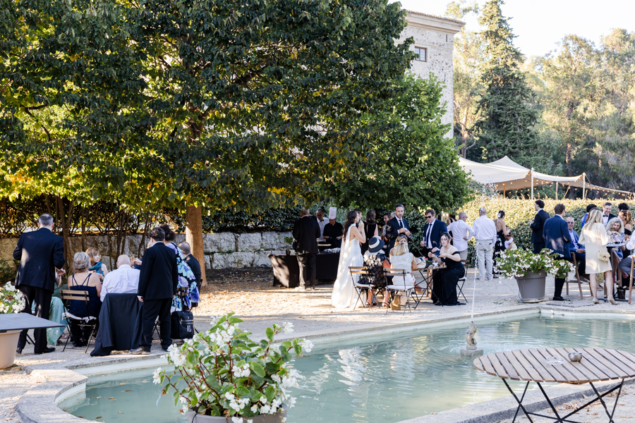 Invités profitant du cocktail de mariage au bord du bassin, avec l'imposante façade du Château de Vaugrenier en arrière-plan.